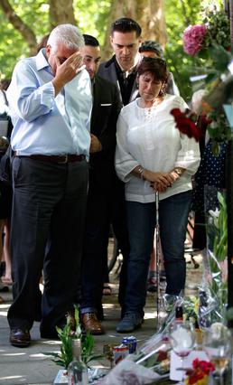 Οι γονείς της Έιμι, Μιτς και Τζάνις Γουάινχαουζ, στέκονται συγκινημένοι στο πρόχειρο  μνημείο  που είχε στηθεί για την κόρη τους, λίγο πριν από τον θάνατό της. Μαζί τους ο τελευταίος σύντροφος της Έιμ